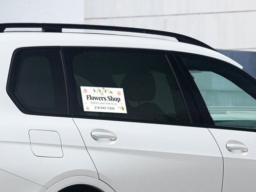 Car window decal promoting a flower shop with bright floral design and branding.