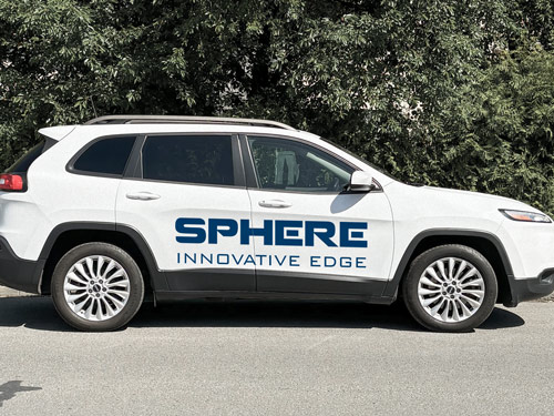 Blue vehicle lettering on white SUV with the brand name parked on the street.