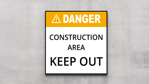 Plastic sign reading Danger Construction Area Keep Out to warn of hazardous site access.