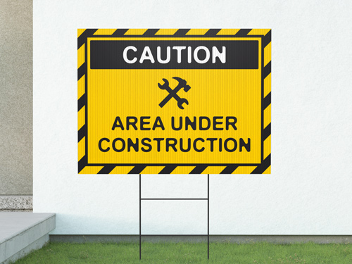 Yellow contractor yard sign on a lawn, designed like a caution sign with bold black text and a construction helmet graphic, promoting construction or remodeling services
