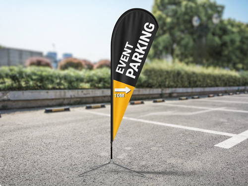 Orange and black teardrop banner flag reading Event Parking on asphalt pavement.