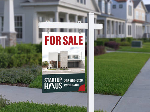 White "For Sale" real estate sign post on residential lawn.
