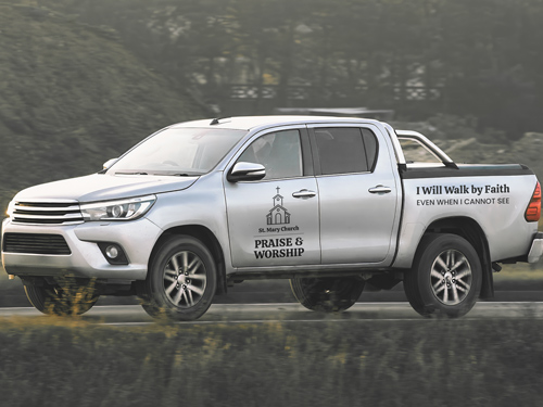 Vinyl lettering on white pickup truck with faith-based messaging and branding.
