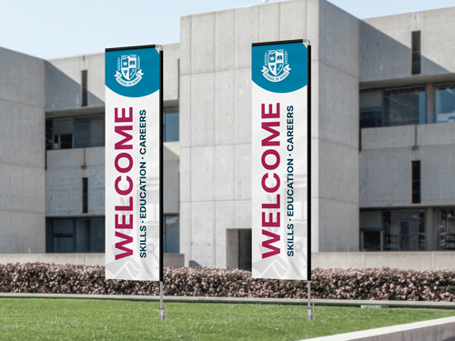 Rectangle flags with a welcoming message displayed outside an institutional building.