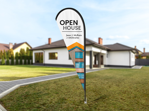 White teardrop banner flag with Open House text on lawn in front of residential home.