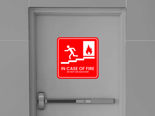 Red reflective sticker with fire, stairs icon and text In case of fire, do not use elevator.