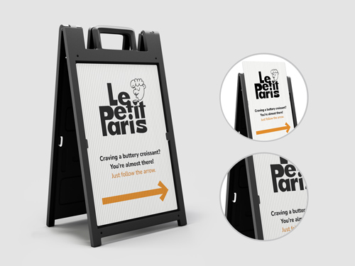 Black sandwich board with coroplast face showing Le Petit Paris logo and a right arrow.