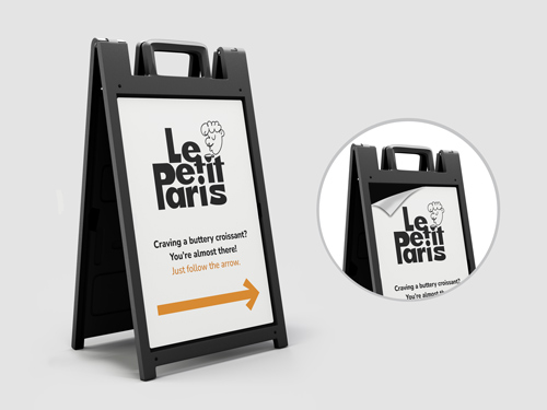 Black sandwich board with opaque vinyl face showing Le Petit Paris logo and a right arrow.
