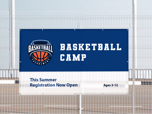 Basketball camp mesh banner on fence with registration open for ages 3-12 this summer.