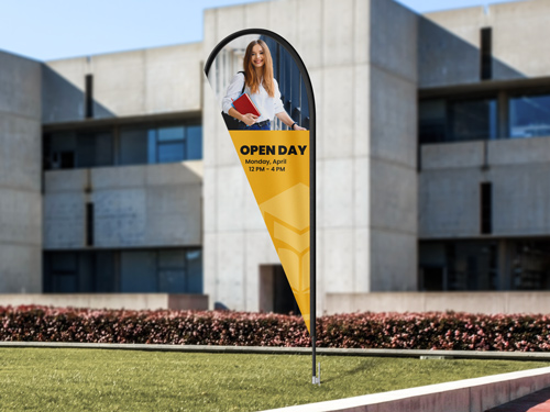 Yellow teardrop banner flag with woman's photo and Open Day text on lawn area.