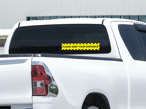 Car window sign displaying a Please Keep Your Distance safety warning message.